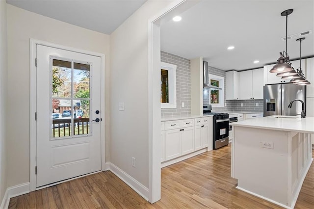 kitchen featuring appliances with stainless steel finishes, backsplash, sink, decorative light fixtures, and white cabinetry