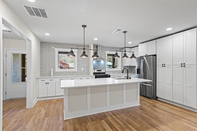 kitchen featuring white cabinetry, sink, hanging light fixtures, and appliances with stainless steel finishes