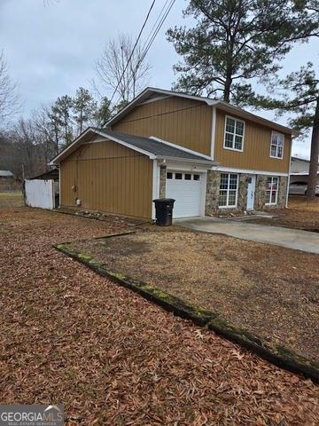 view of side of home featuring stone siding, concrete driveway, and a garage