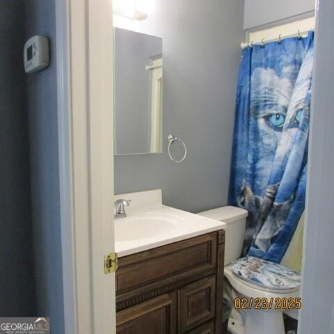 bathroom featuring toilet, vanity, and a shower with curtain