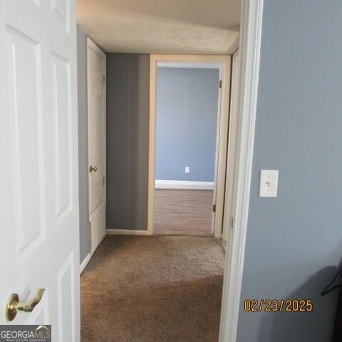 hall featuring carpet flooring and baseboards