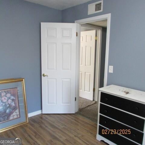 bedroom with visible vents, baseboards, and wood finished floors