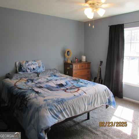 carpeted bedroom featuring multiple windows and a ceiling fan