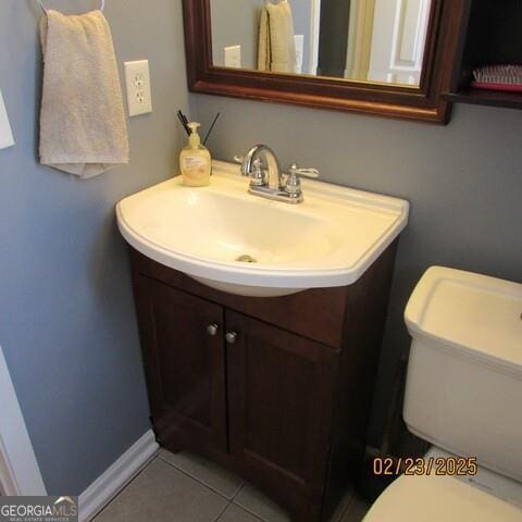 half bath with vanity, tile patterned floors, and toilet