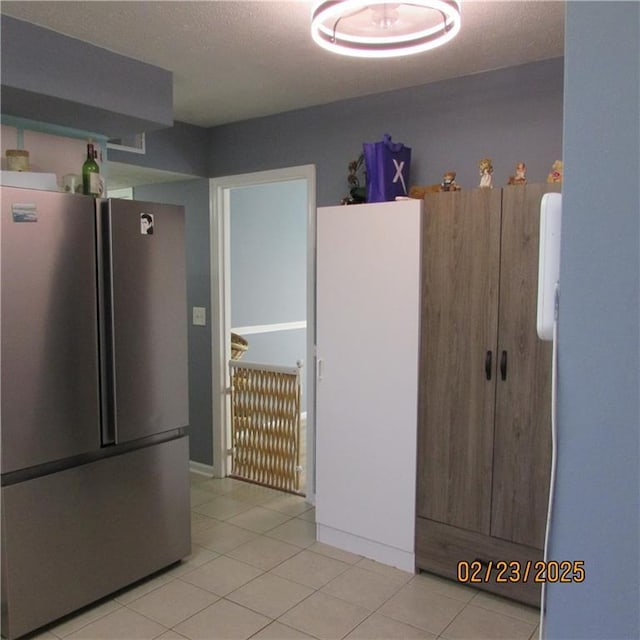 kitchen featuring light tile patterned flooring, freestanding refrigerator, and a textured ceiling