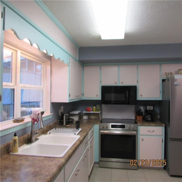 kitchen featuring a sink, a textured ceiling, light tile patterned flooring, and stainless steel appliances