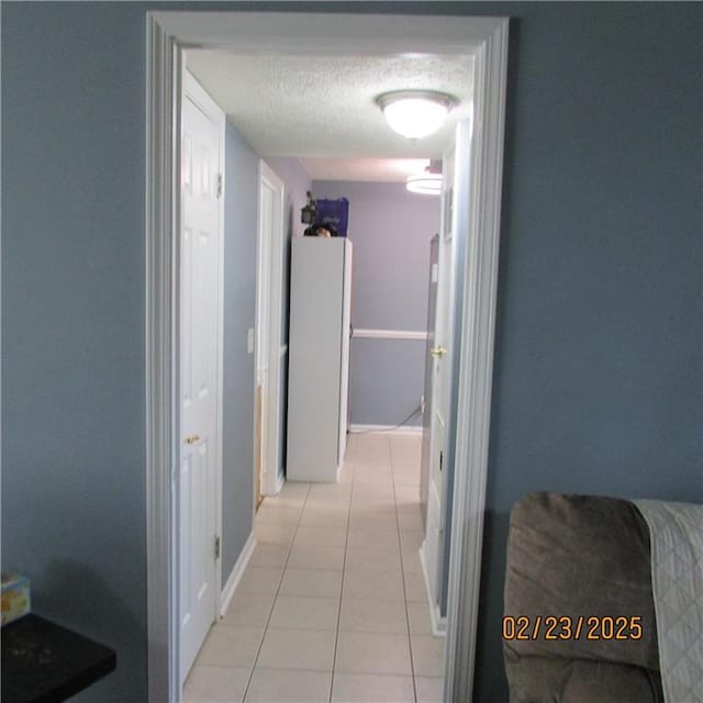 corridor with light tile patterned floors and a textured ceiling