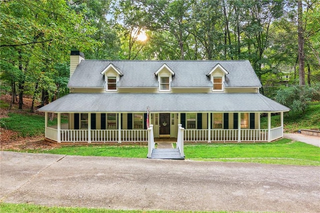 farmhouse-style home with a porch, a front yard, and a chimney