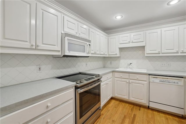 kitchen featuring light hardwood / wood-style floors, sink, white appliances, tasteful backsplash, and white cabinets