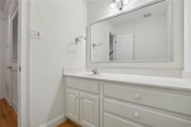 bathroom featuring ornamental molding, vanity, and wood-type flooring