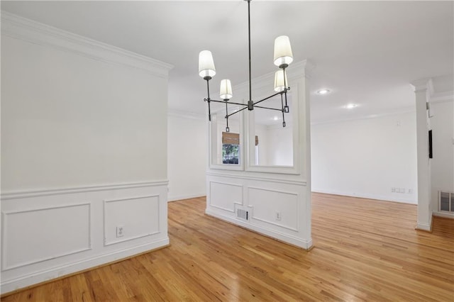 unfurnished dining area featuring light hardwood / wood-style floors, an inviting chandelier, and crown molding