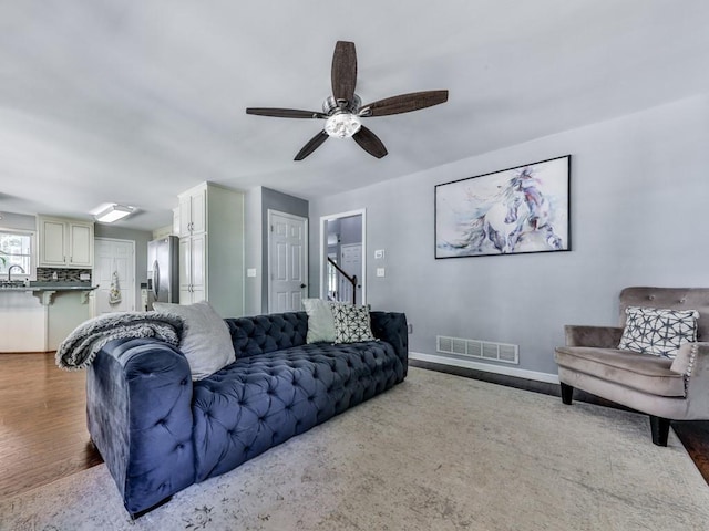 living area featuring a ceiling fan, wood finished floors, and baseboards