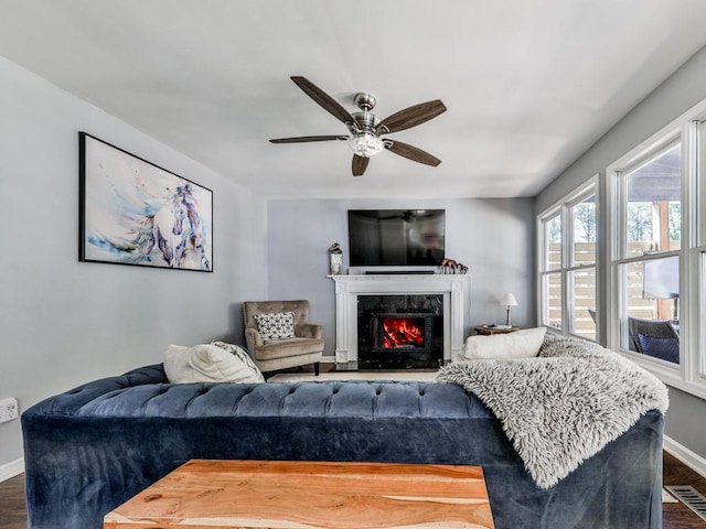 living room with baseboards, dark wood-style flooring, a high end fireplace, and a ceiling fan