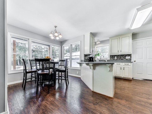 kitchen with a chandelier, dark countertops, baseboards, and a breakfast bar area