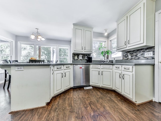 kitchen featuring stainless steel dishwasher, a peninsula, dark wood-type flooring, decorative backsplash, and a chandelier