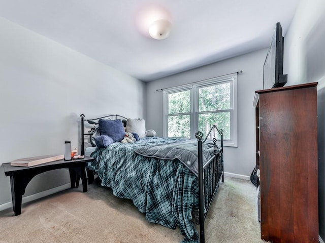 bedroom with light colored carpet and baseboards