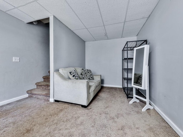 sitting room featuring a drop ceiling, carpet floors, and baseboards