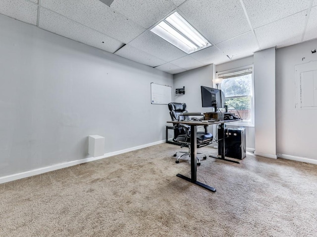 carpeted office space featuring a drop ceiling and baseboards