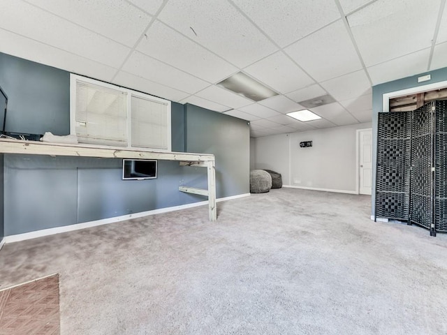 below grade area featuring a drop ceiling, carpet, and baseboards
