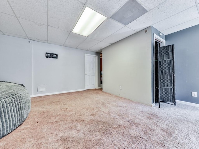 finished basement with a drop ceiling, carpet, and baseboards