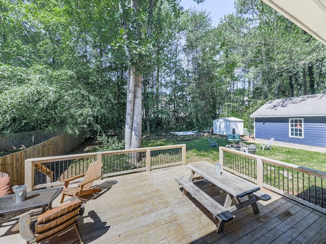wooden terrace featuring an outbuilding, a storage shed, and a yard