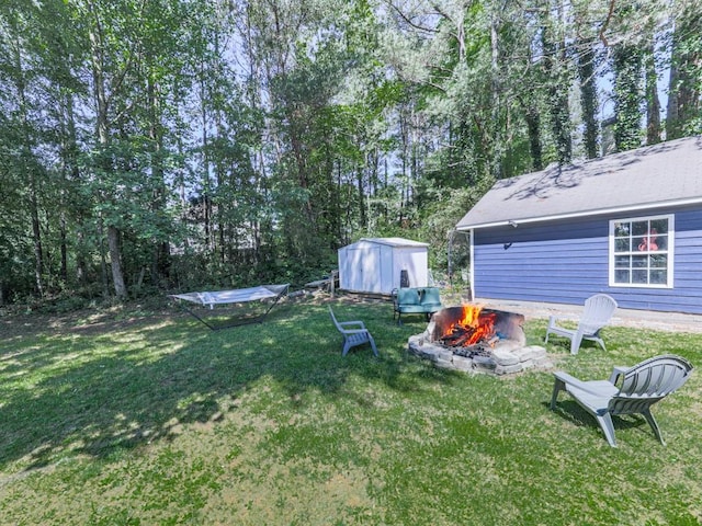 view of green lawn featuring an outdoor fire pit, a storage unit, and an outdoor structure