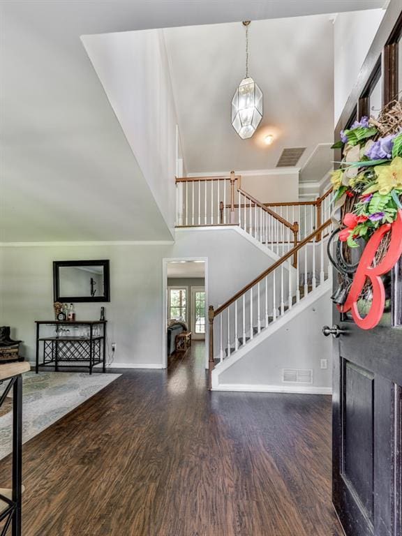 entrance foyer with a towering ceiling, wood finished floors, stairs, and baseboards