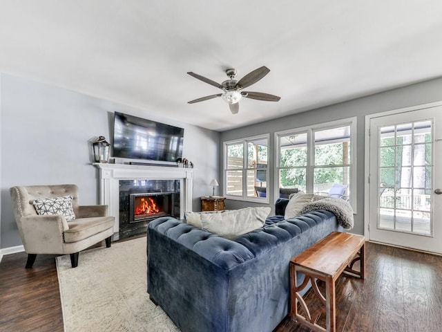 living area with plenty of natural light, ceiling fan, dark wood-style floors, and a high end fireplace