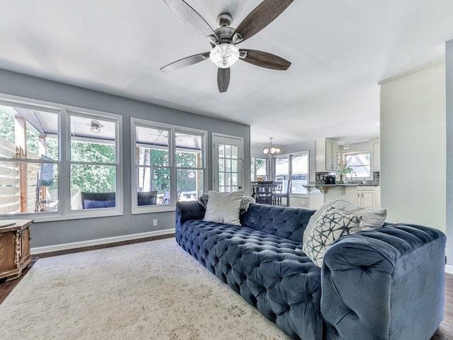 living room with baseboards, dark wood finished floors, ceiling fan, and a chandelier