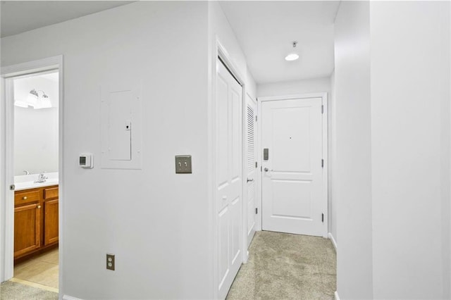 hallway with electric panel, sink, and light colored carpet