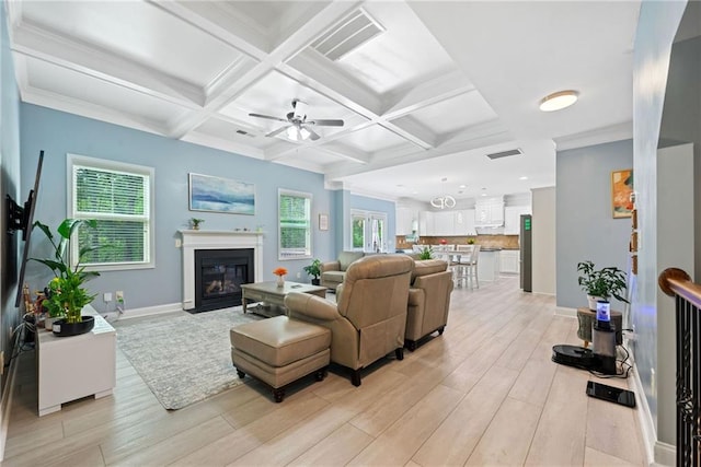 living area featuring visible vents, light wood-style flooring, a ceiling fan, and beam ceiling