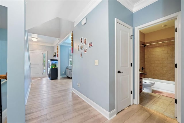 hall featuring light wood-style flooring, baseboards, and ornamental molding