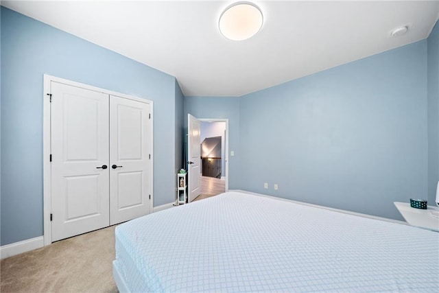 bedroom with a closet, baseboards, and light colored carpet