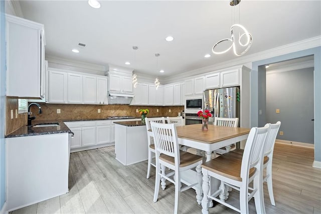 dining room with crown molding, light wood finished floors, baseboards, and recessed lighting
