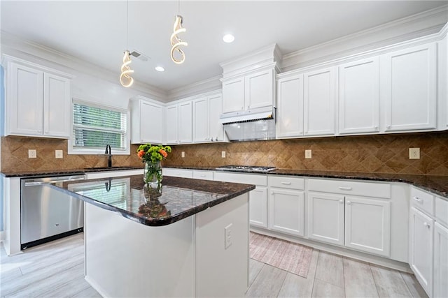 kitchen with dark stone countertops, white cabinetry, crown molding, appliances with stainless steel finishes, and a sink