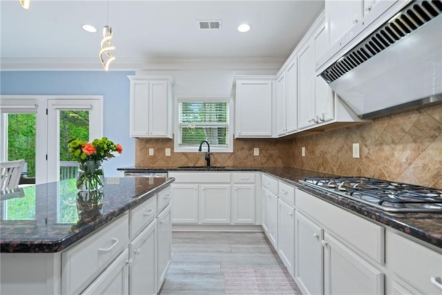 kitchen with under cabinet range hood, a sink, stainless steel gas cooktop, and ornamental molding