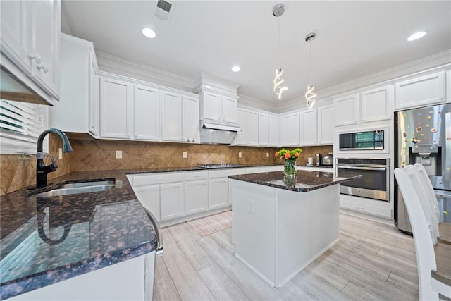 kitchen with white cabinets, visible vents, dark stone counters, stainless steel appliances, and a sink