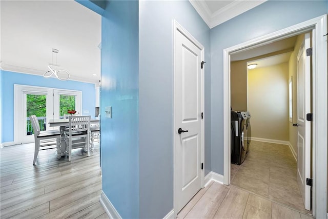 corridor with washer and dryer, crown molding, baseboards, and light wood-type flooring