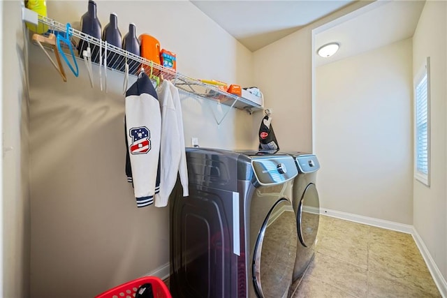 clothes washing area featuring washing machine and clothes dryer, laundry area, and baseboards