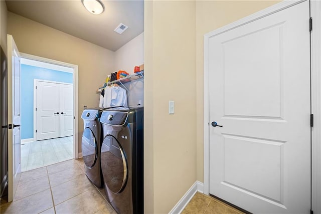 washroom featuring visible vents, baseboards, washer and dryer, laundry area, and light tile patterned flooring
