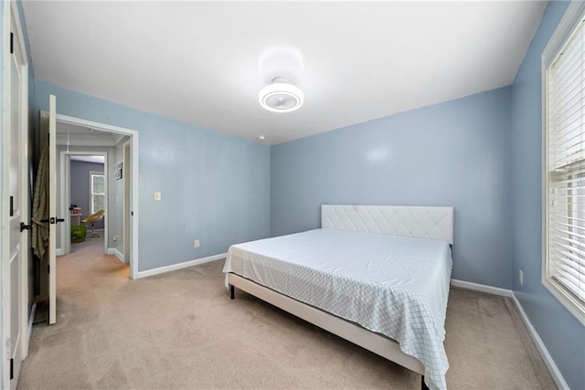 bedroom featuring baseboards and light colored carpet