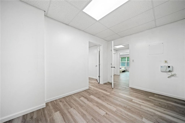 spare room featuring wood finished floors, baseboards, and a drop ceiling