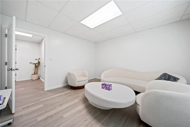sitting room featuring baseboards, a paneled ceiling, and wood finished floors