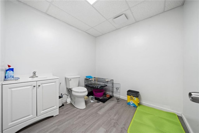 bathroom with toilet, a paneled ceiling, wood finished floors, and baseboards