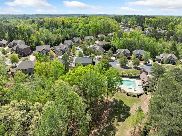 drone / aerial view featuring a wooded view and a residential view