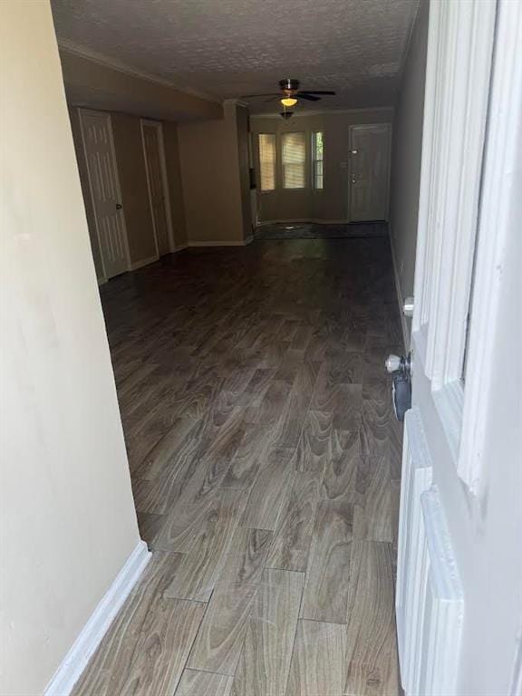 hall featuring baseboards, a textured ceiling, and wood finished floors