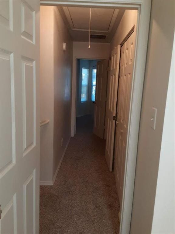 hallway featuring baseboards, light colored carpet, and attic access