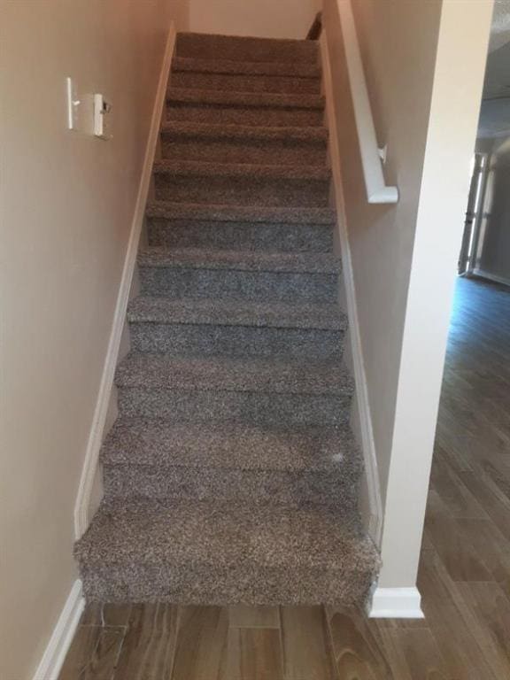 staircase featuring baseboards and wood finished floors