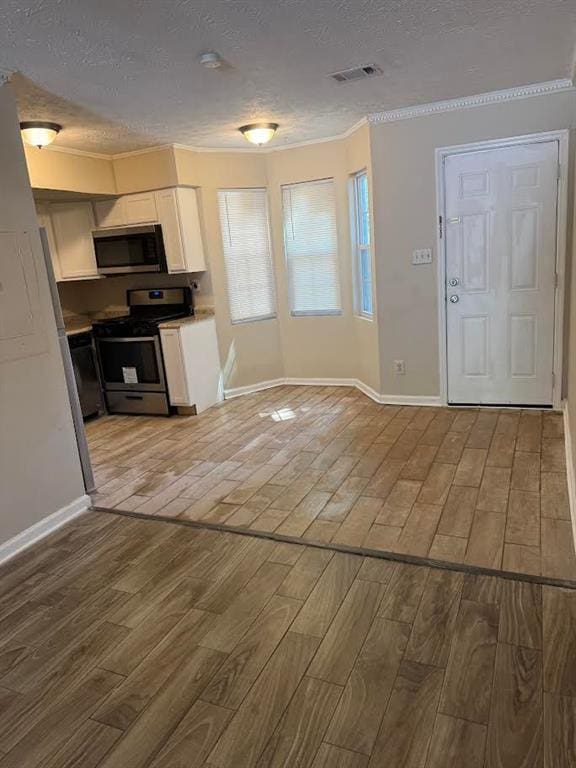 kitchen with stainless steel appliances, a textured ceiling, visible vents, and light wood finished floors