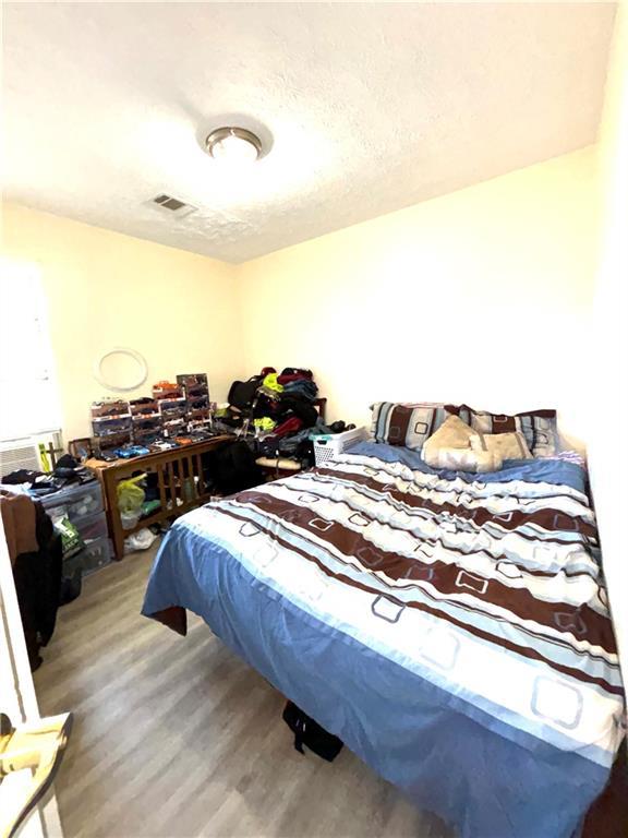 5687 Pine Meadow Ct, Morrow, GA 30260 - bedroom featuring visible vents, wood finished floors, and a textured ceiling